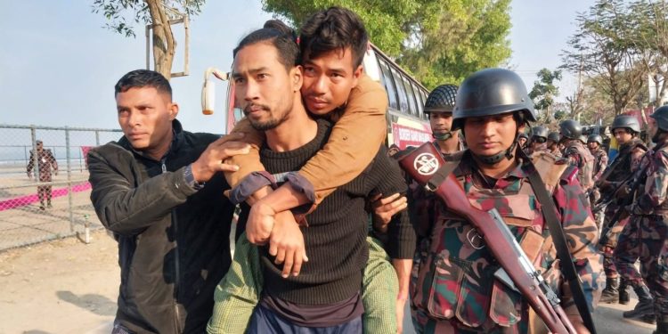 Escorted by Bangladesh Border Guard officers, a Myanmar junta soldier carries an injured colleague to the Inani naval jetty in Cox’s Bazar, Bangladesh in February 2024. / Mohibbullah Mohib