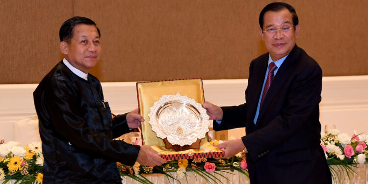 Then-Cambodian Prime Minister Hun Sen (right) offers a souvenir to Myanmar military chief Min Aung Hlaing during a dinner in Naypyitaw in January 2022. / AFP
